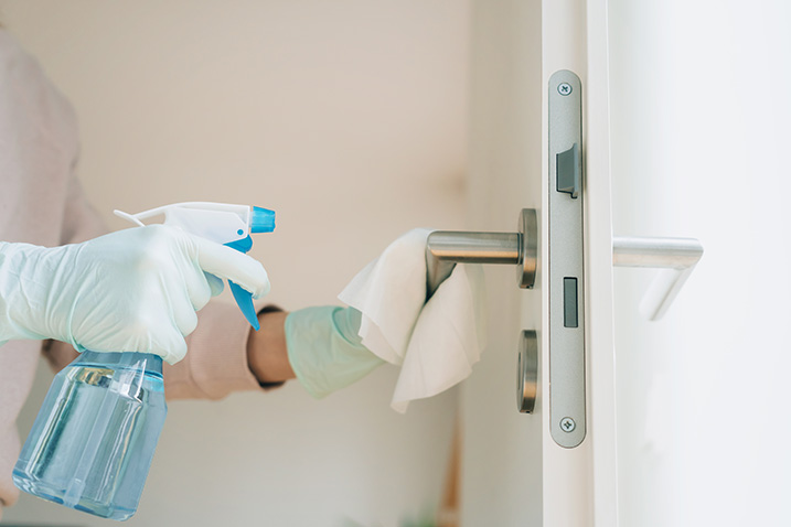 person disinfecting door handle
