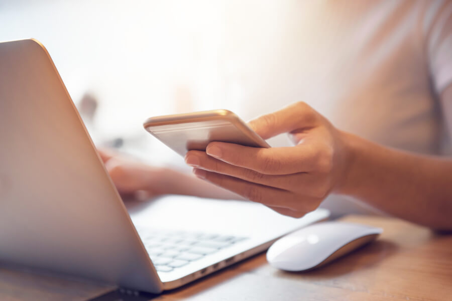 Closeup of a patient using her cellphone and laptop to stay informed on the coronavirus pandemic