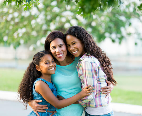 smiling mother being hugged by her two daughters