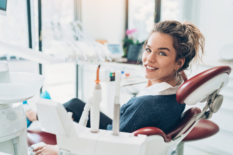 Brunette woman in a dental chair smiles before receiving a tooth extraction in Lowell