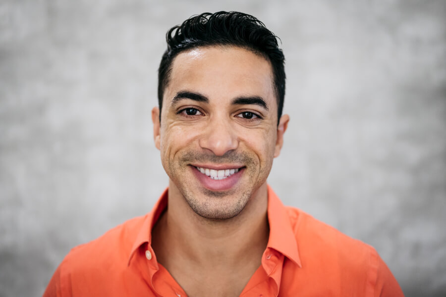 Man with all his natural teeth smiles while wearing an orange shirt in Lowell, MA