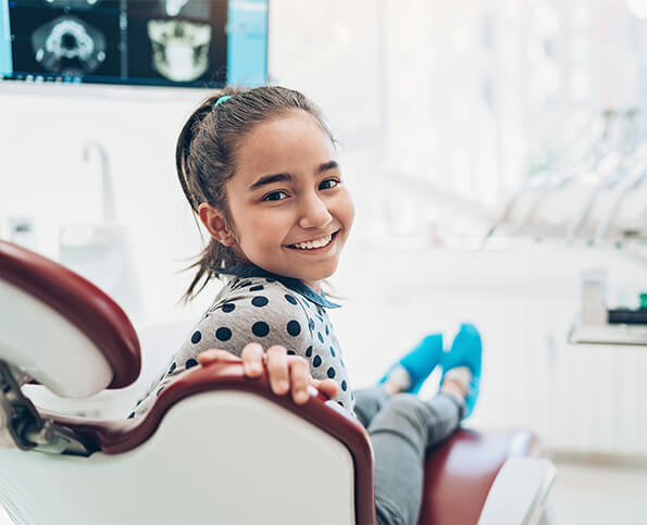 young, smiling girl sitting in a dental chair