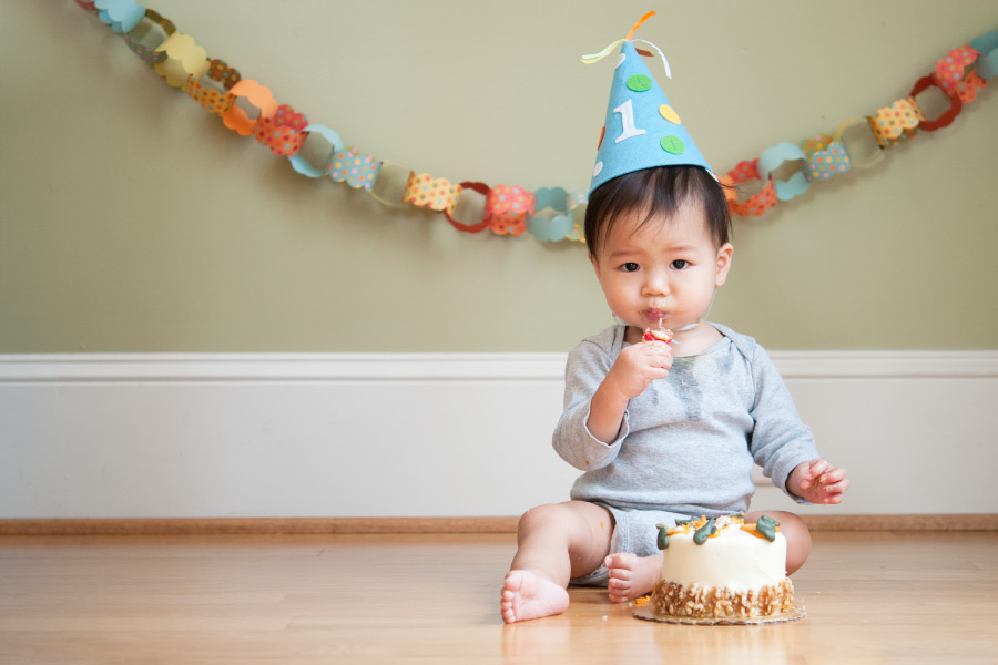 Little boy wears a party hat with a 1 on it to celebrate his first birthday